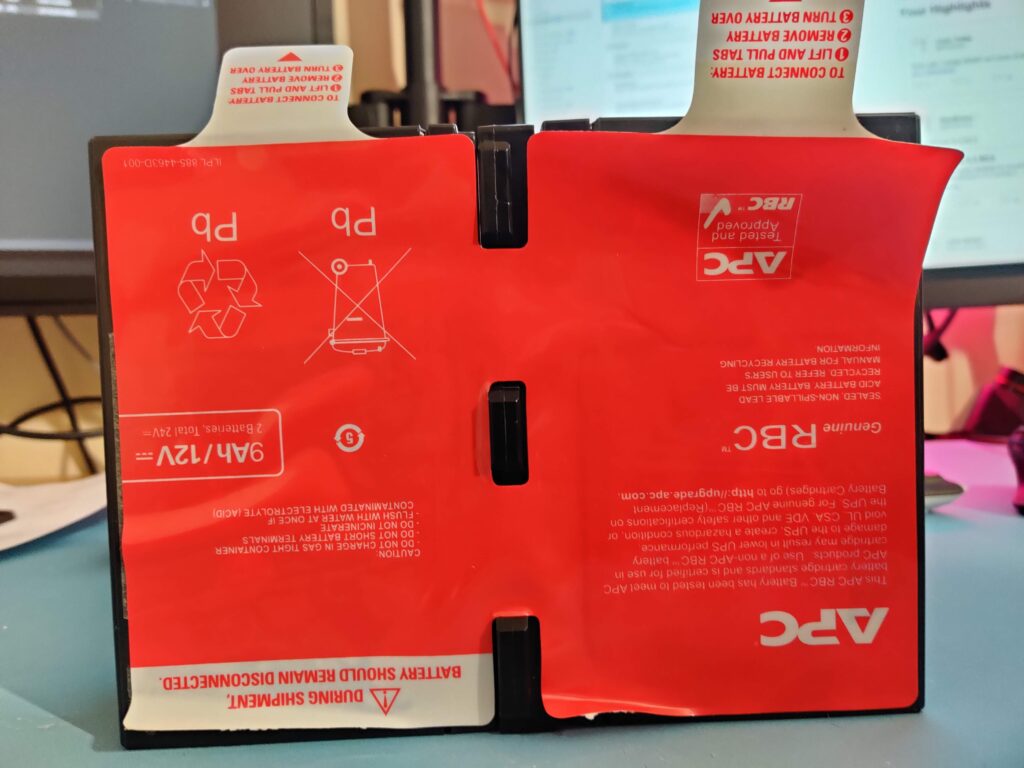 The other face of the red plate — Genuine RBC, 9Ah/12V, two batteries, 24V total, with the recycling and caution symbols