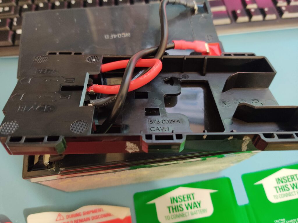 The connector holder lifted clear, its red and black leads crossing the moulding marked 876-0029A