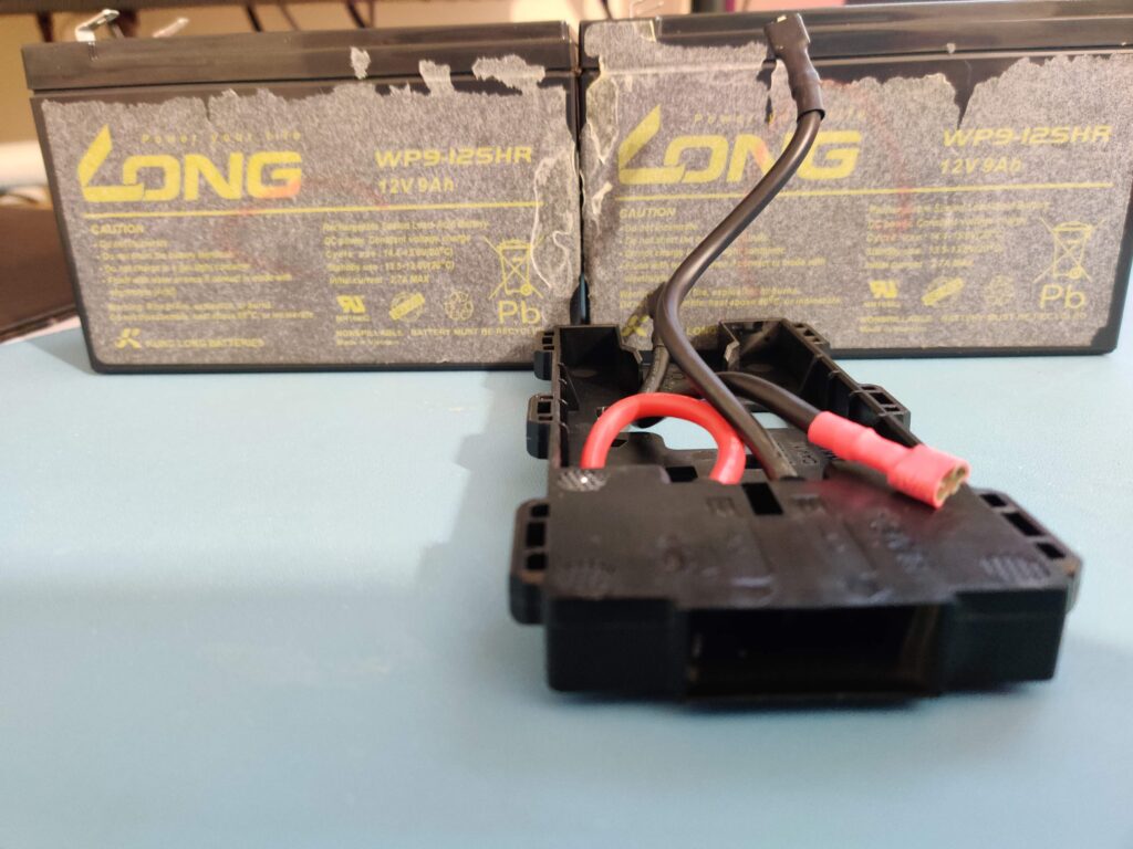 The holder on the desk with both LONG WP9-12SHR 12V 9Ah cells standing behind it