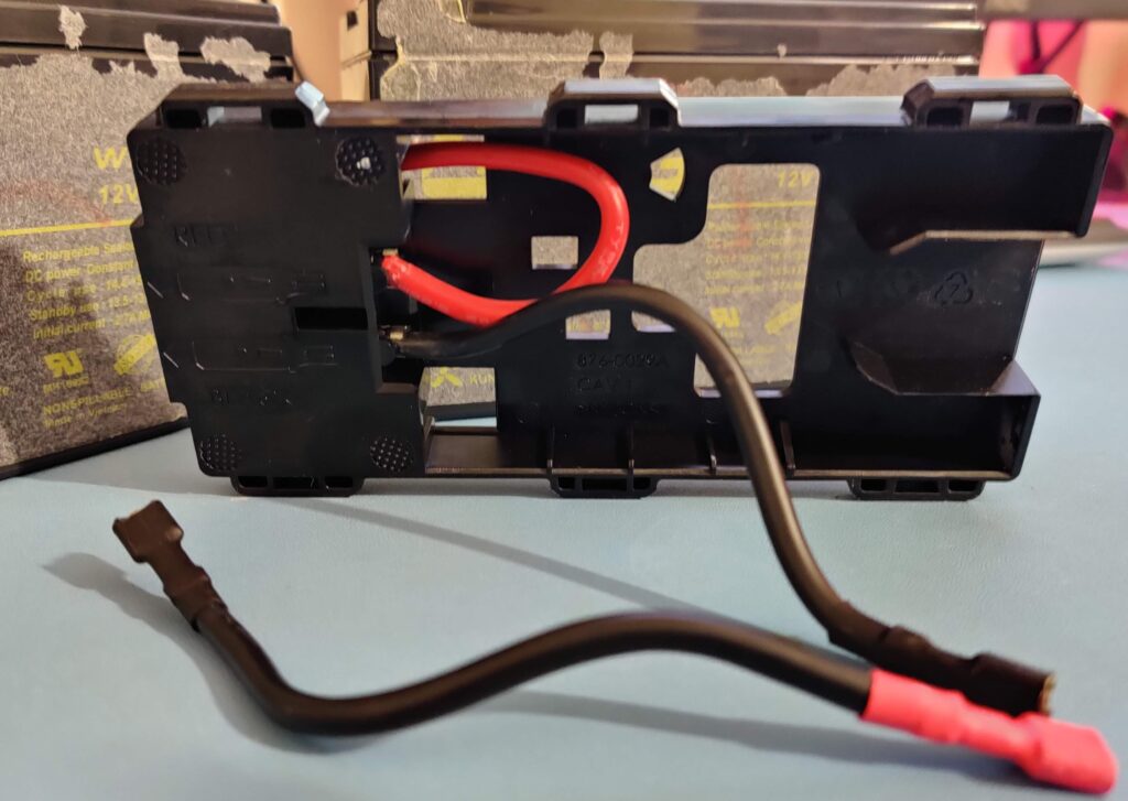 The holder from the front, one lead coiled inside it and one hanging loose