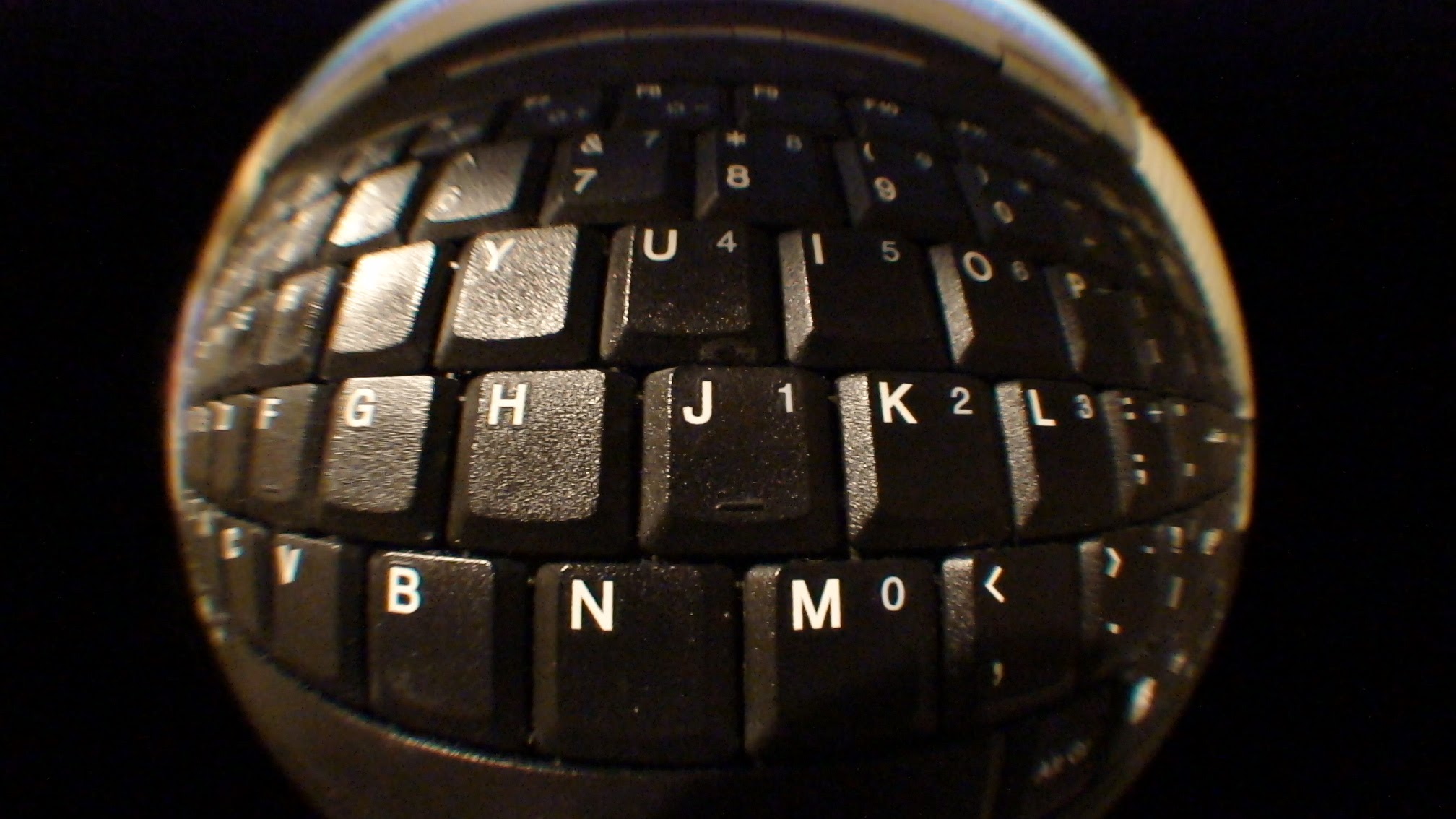 A laptop keyboard photographed through a glass sphere